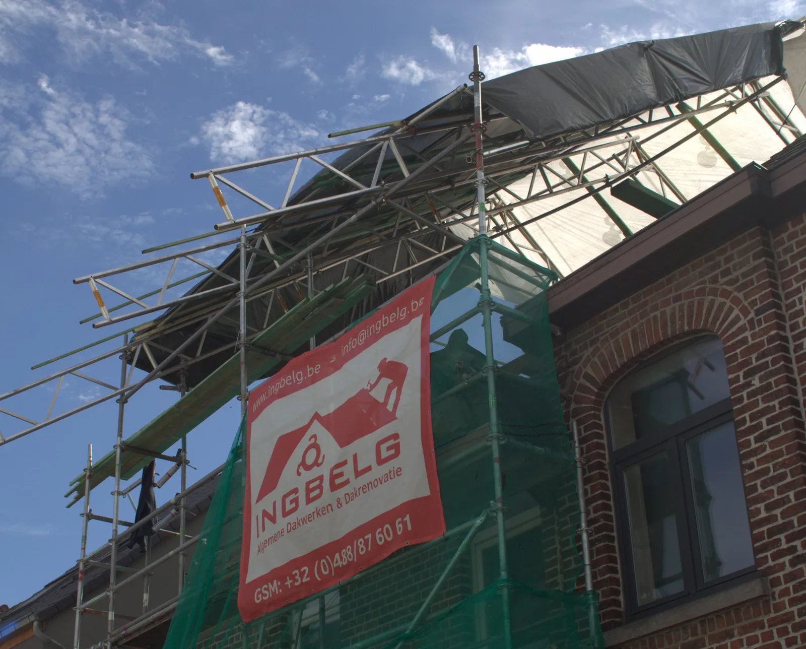 Dakliggers en steiger onder het afdekzeil, met het INGBELG-spandoek